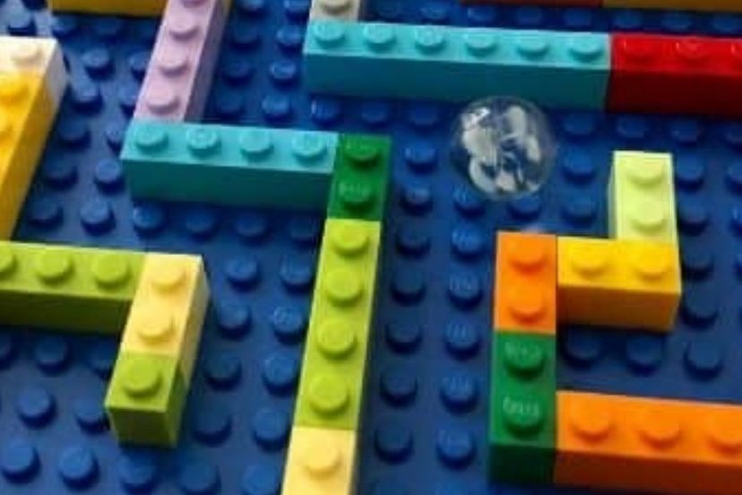 Labyrinthe en briques de couleur sur une plaque bleue, avec une bille en verre